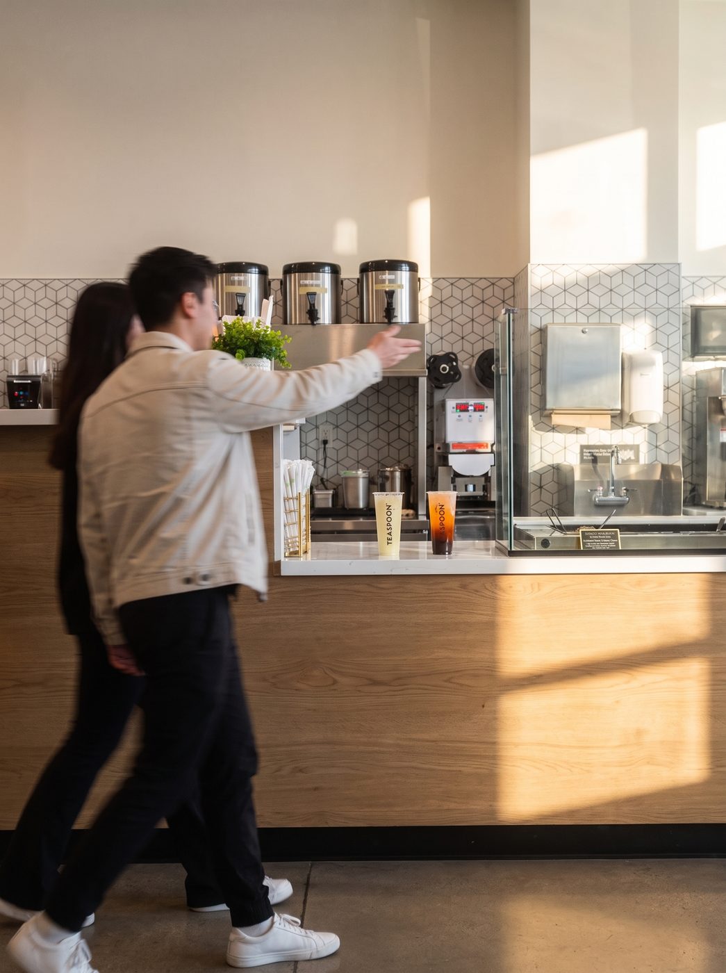 Two prospective partners touring a Teaspoon store, pointing at the brewing counter.