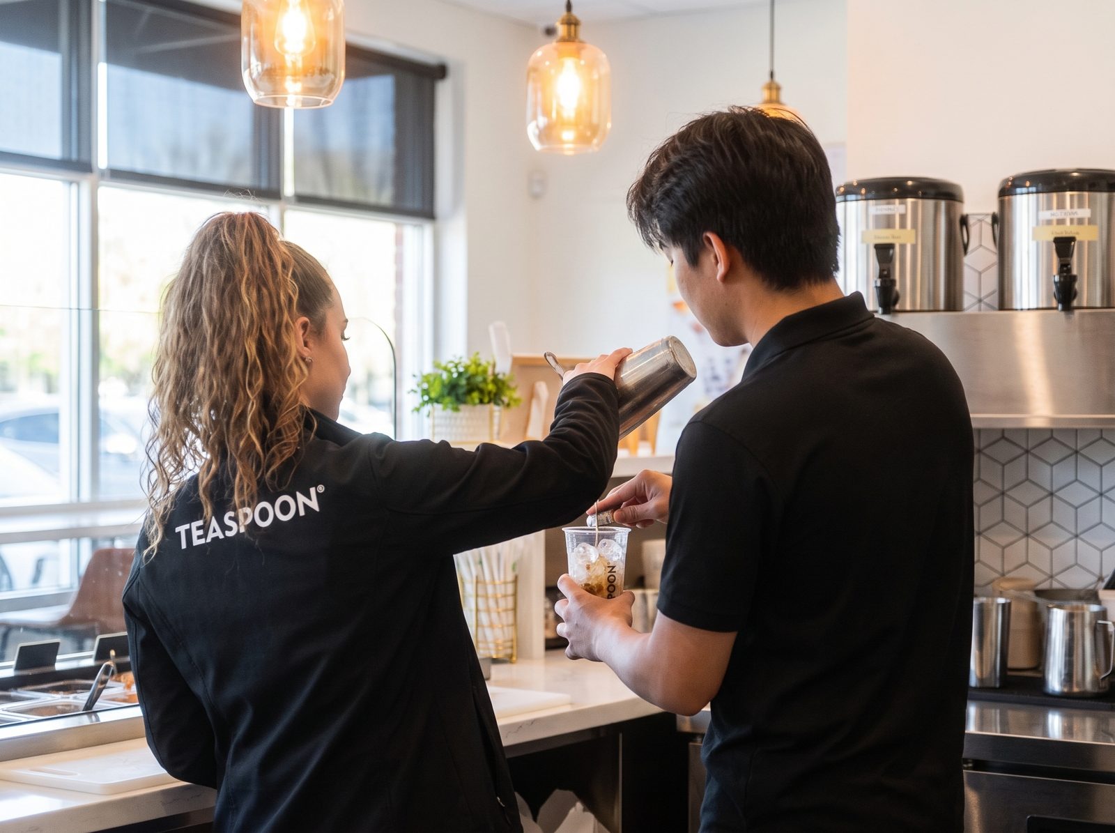 A Teaspoon trainer showing a new team member how to build a drink behind the counter.